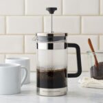 A glass French Press coffee maker with freshly brewed coffee.