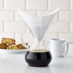 A glass Pour Over coffee maker with a filter and coffee brewing inside.