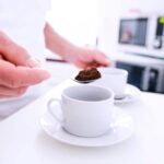 Instant coffee granules in a wooden spoon, with warm bokeh lights in the background.